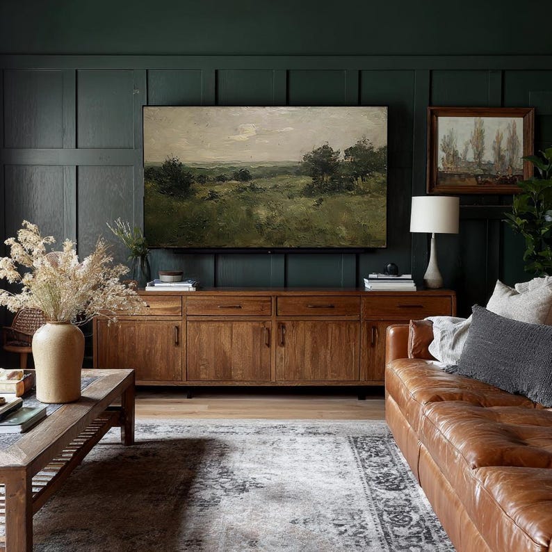 May include: A living room with a dark green paneled wall, featuring a large landscape painting above a wooden cabinet. A brown leather sofa and a patterned rug complete the space. A lamp and decorative vase are also visible.