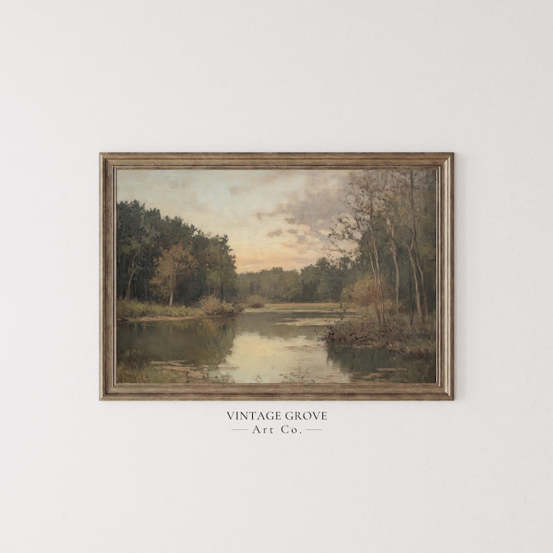 May include: A framed painting depicting a lake scene with trees lining either side of the water. The sky is a soft blue with a few clouds. The water is calm and reflective. The painting is in a brown frame.