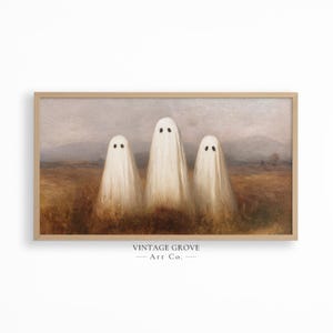 May include: A framed print featuring three white ghost figures with black eyes standing in a field. The artwork has a vintage aesthetic with a muted color palette and a light brown wooden frame. The text "VINTAGE GROVE - Art Co." is at the bottom.
