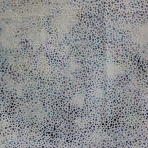 May include: A fabric with a speckled pattern. The background is a light cream colour, with a scattering of small, dark blue and grey dots. The fabric has a slightly textured appearance.