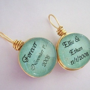 May include: Two gold wire wrapped pendants with aqua blue glass circles. One pendant says "Forever November 1st, 2008" and the other says "Ellie & Ethan 11/1/2008".