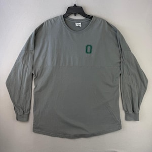 May include: A gray long-sleeve shirt with a crew neck and a green number "0" on the chest. The shirt is made of a soft material and has a relaxed fit. The sleeves have ribbed cuffs.