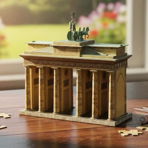 May include: A miniature model of the Brandenburg Gate, a famous landmark in Berlin, Germany, is assembled on a wooden surface. The model is tan and gold, with a detailed design. Puzzle pieces and glue are scattered around the model.