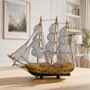 May include: A wooden model sailboat with white and gray striped sails and a brown hull. The model sits on a wooden base and is displayed on a light-colored wooden surface. The ship has multiple masts and rigging.