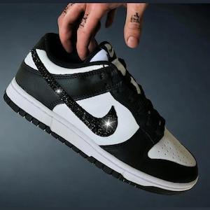 May include: Black and white low-top sneakers with a black swoosh and a row of rhinestones on the side.