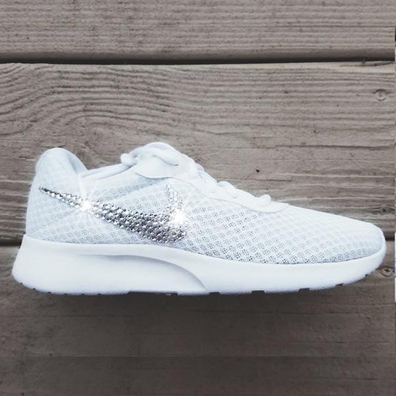 Puede incluir: Zapatilla deportiva blanca con parte superior de malla y suela blanca. El logotipo de Nike swoosh est&aacute; adornado con pedrer&iacute;a plateada. El zapato est&aacute; dise&ntilde;ado para la comodidad y el estilo.