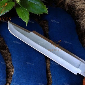 May include: A silver knife with a black handle and the word "PREDATOR" printed on the blade. The knife is lying on a blue surface.