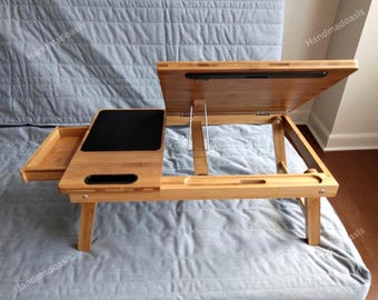 May include: A natural bamboo laptop desk with a black surface for a mouse and a tilting top. The desk has a pull-out drawer and adjustable legs. The desk is 28 inches long, 14 inches wide, and 10 inches high.