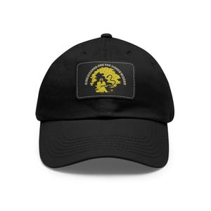 May include: Black baseball cap with a yellow patch featuring the text "King Gizzard and the Lizard Wizard" and a graphic of a person sitting on a tree branch with a snake.