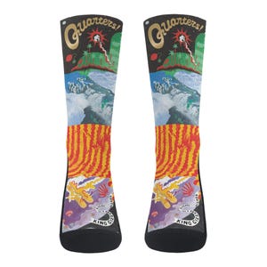 Peut inclure: Une paire de chaussettes noires avec un motif coloré représentant une scène de montagne, un motif rayé et le texte "Quarters! King Gizz Wizard Lizards"