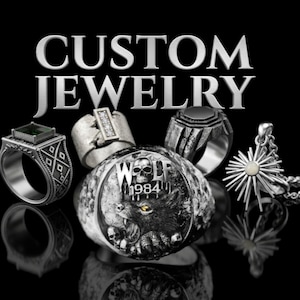 Op de afbeelding: Een assortiment aangepaste zilveren sieraden tegen een zwarte achtergrond. De afbeelding toont ringen met verschillende ontwerpen, waaronder een wolf, een schedel en geometrische patronen. Een hanger met een zonnesterontwerp is ook zichtbaar. De tekst "CUSTOM JEWELRY" staat bovenaan.