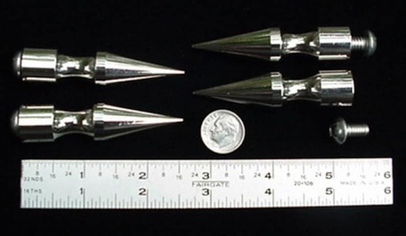 Puede incluir: Cuatro puntas de metal plateado con un extremo roscado. Las puntas miden aproximadamente 5 cm de largo y tienen una punta puntiaguda. Se incluye una regla para la escala.