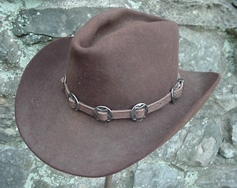 May include: A brown felt cowboy hat with a leather band and silver accents.