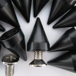 May include: A close-up of a group of black metal spikes with a silver screw base. The spikes are pointed and have a conical shape.