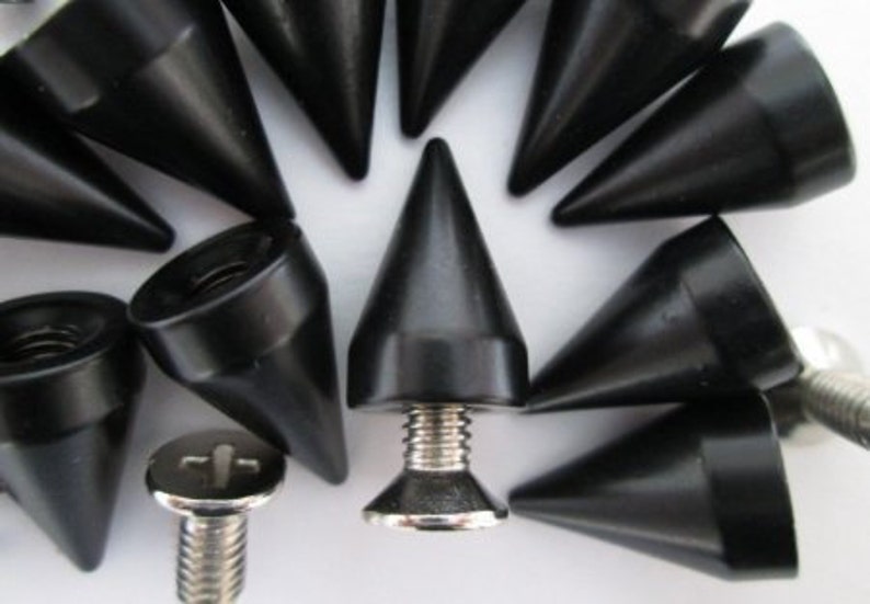 May include: A close-up of a group of black metal spikes with a silver screw base. The spikes are pointed and have a conical shape.