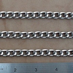 Puede incluir: Tres extensores de chaqueta vaquera de cadena plateada con lengüetas de cuero negro y broches metálicos. Los extensores se muestran contra una regla con marcas en pulgadas.