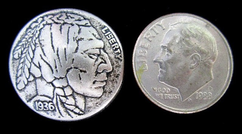 May include: Two silver coins on a black background. One coin features a Native American profile with the year 1936. The other coin shows a profile of a man with the year 1988. Both coins have the word "LIBERTY" on them.