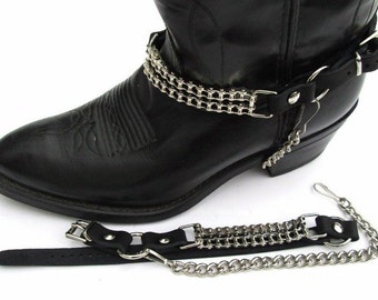 May include: A pair of black leather boot straps with silver chains. The straps are designed to be worn around the ankle of a boot and have a buckle closure. The chains are attached to the straps and hang down the side of the boot.