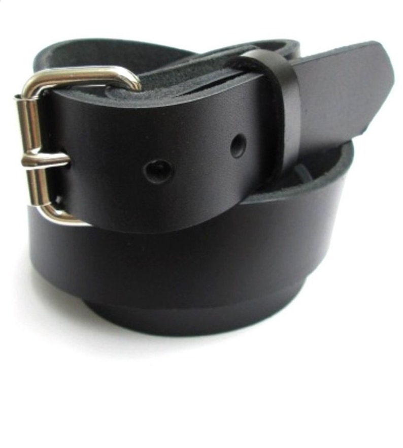 May include: A black leather belt with a silver buckle. The belt is folded in half and the buckle is visible.