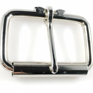 May include: A silver metal buckle with a rectangular shape and a smooth finish.