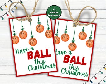 May include: Two gift tags with a red border and the text "Have a BALL this Christmas". Each tag features basketball ornaments hanging from green strings. A string loop is at the top for hanging.