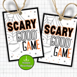 May include: Two Halloween-themed gift tags with the words "SCARY GOOD GAME" in black and orange, with a baseball graphic. The tags have a white background with a spiderweb and star design. Each tag has a brown string.