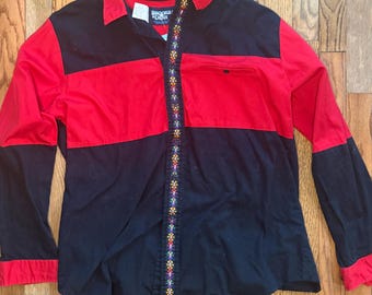May include: A long-sleeved button-down shirt with a color-block design. The top half is red, and the bottom half is black. The shirt has a floral embroidered detail down the front and a small pocket on the chest. The label reads "Brooks & Dunn".