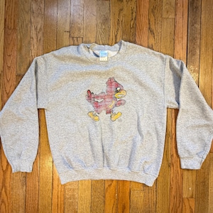 May include: A light gray sweatshirt featuring a cartoon cardinal in red, yellow, and white. The cardinal is walking with a determined expression. The sweatshirt has long sleeves and a crew neck.