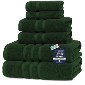 May include: A six-piece set of dark green Turkish cotton towels. The towels are stacked, displaying their soft texture. A tag indicates the set is made of 100% cotton. The towels are a deep forest green.