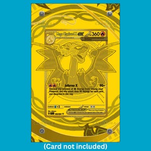 May include: A rectangular gold-coloured display case featuring a central graphic of a Mega Charizard X EX trading card with 360 HP and the Inferno X attack. The case has four silver-toned corner fasteners and a decorative circular pattern.