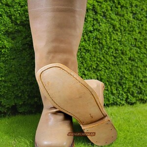 May include: A pair of brown leather knee-high boots with a pointed toe and a thick sole. The boots are made of a soft, supple leather and have a classic, timeless design.