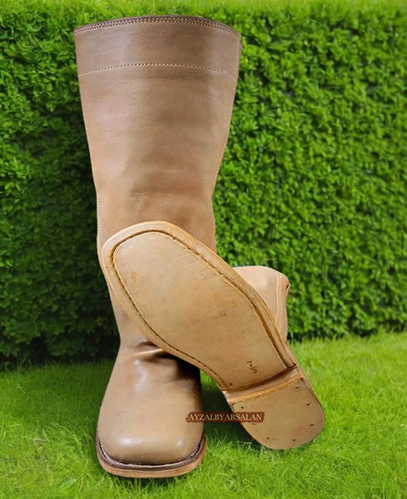 May include: A pair of brown leather knee-high boots with a pointed toe and a thick sole. The boots are made of a soft, supple leather and have a classic, timeless design.