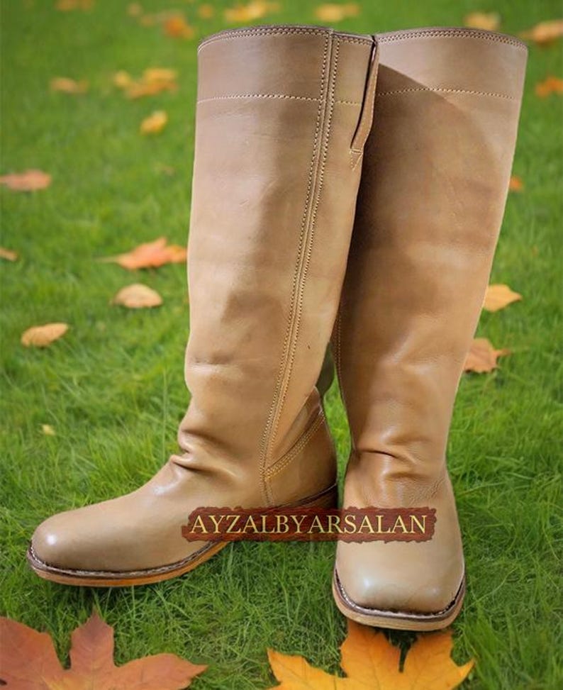 May include: A pair of tan leather knee-high boots with a pointed toe and a slight heel. The boots are made of a soft, supple leather and have a classic, timeless design.