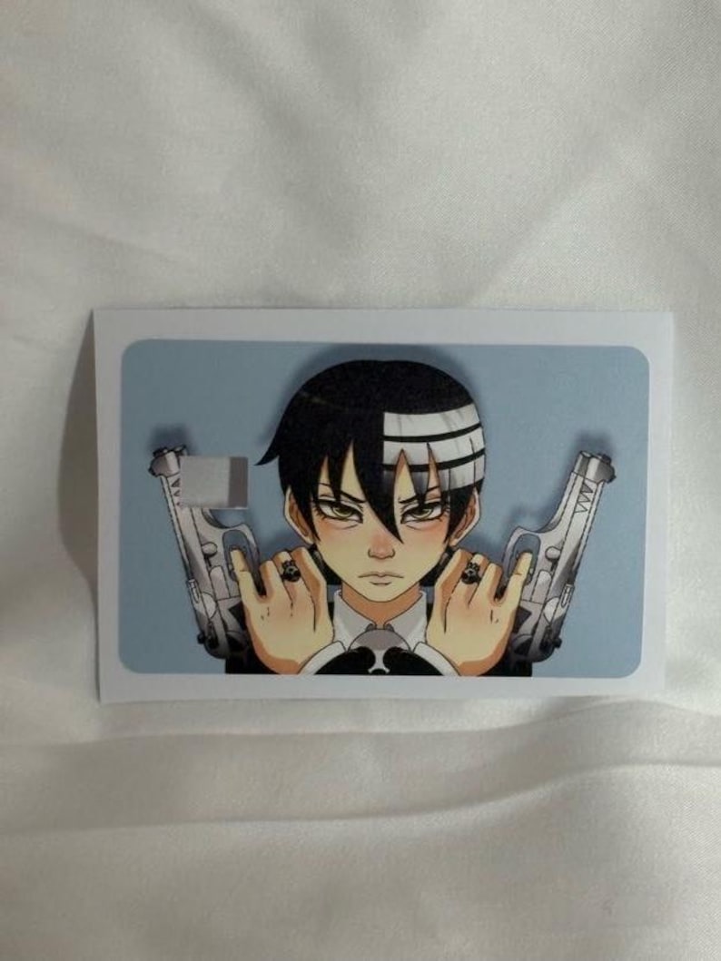 Op de afbeelding: Een rechthoekige sticker met een anime-personage met zwart en wit haar, die twee zilveren pistolen vasthoudt. Het personage heeft een serieuze uitdrukking en draagt een zwart pak met een witte kraag. De achtergrond is lichtblauw.
