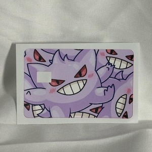 Op de afbeelding: Een witte rechthoekige sticker met een herhaald patroon van een paars stripfiguur spook. Het personage heeft een ondeugende grijns, rode ogen, een stekelige kop en blozende wangen.