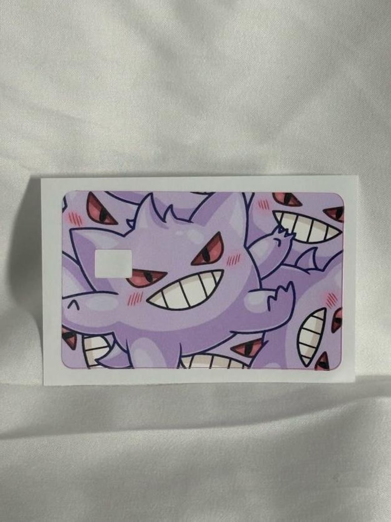 Op de afbeelding: Een witte rechthoekige sticker met een herhaald patroon van een paars stripfiguur spook. Het personage heeft een ondeugende grijns, rode ogen, een stekelige kop en blozende wangen.