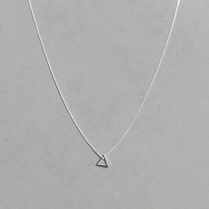 May include: A silver chain necklace with a small, simple triangle pendant.