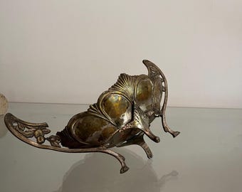 May include: An antique silver-toned metal decorative piece with an ornate, floral design. The piece has a curved, boat-like shape with intricate detailing, including a central, textured section and delicate, curved supports. The metal has a tarnished, aged appearance.