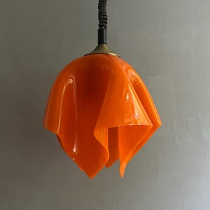 May include: Orange pendant light with a ruffled, flower-shaped shade.