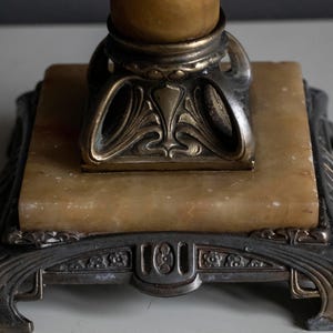 May include: A vintage lamp base with a marble base and ornate metal accents. The base is square with a decorative design around the edges. The metal accents are gold and silver.