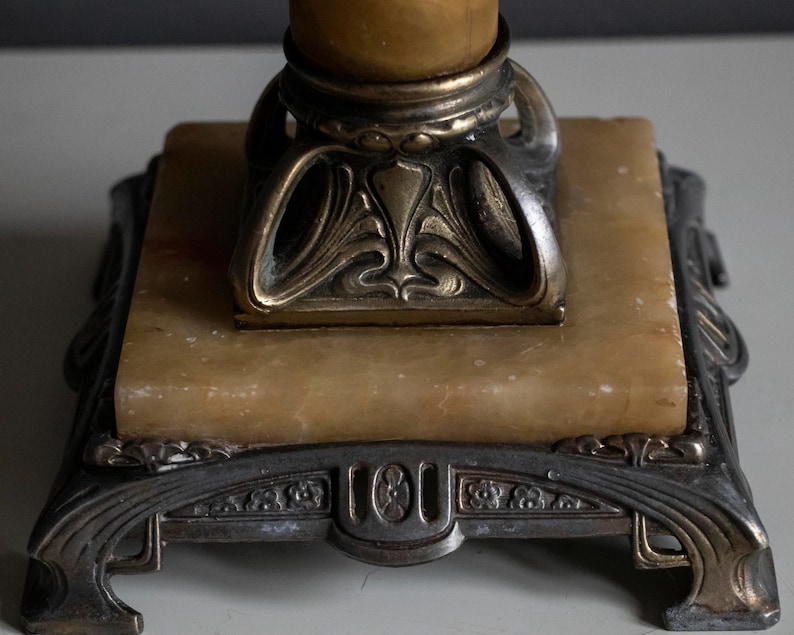 May include: A vintage lamp base with a marble base and ornate metal accents. The base is square with a decorative design around the edges. The metal accents are gold and silver.