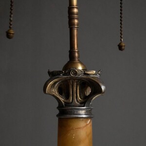 May include: A vintage table lamp with a marble base and a brass and silver finish. The lamp has a decorative, ornate design with a chain pull switch.