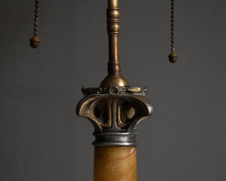 May include: A vintage table lamp with a marble base and a brass and silver finish. The lamp has a decorative, ornate design with a chain pull switch.