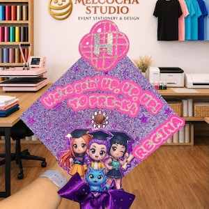 Puede incluir: Un adorno para birrete de graduación con purpurina morada que incluye el texto "We're goin' up, up, up! TO PRE-K!" y el nombre "REGINA". Presenta una letra "H" central, tres personajes de dibujos animados, un gato azul y un lazo de satén morado.
