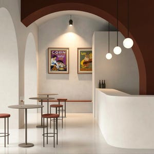 May include: A modern interior space featuring a curved white bar, round tables with thin metal bases, and matching stools with rust-colored seats. Two vintage-style posters hang on the wall, and three spherical pendant lights hang from the ceiling.