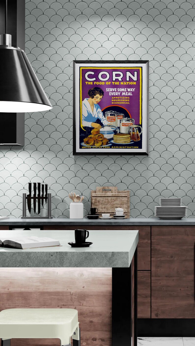 May include: A framed vintage poster titled CORN THE FOOD OF THE NATION, featuring an illustration of a person preparing corn-based dishes. The text includes SERVE SOME WAY EVERY MEAL, APPETIZING NOURISHING ECONOMICAL, and UNITED STATES FOOD ADMINISTRATION.