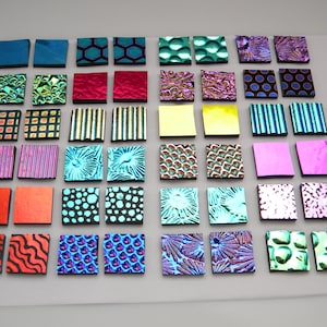 May include: A display of 42 square tiles in a range of colours and textures. The tiles feature patterns such as stripes, dots, and geometric designs, in shades of blue, green, red, yellow, and purple. The tiles are arranged in a grid.