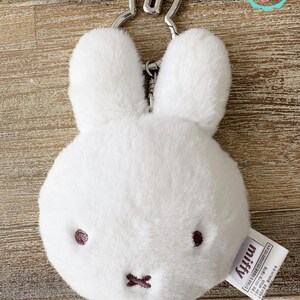 May include: A white plush bunny keychain with a silver-colored metal keyring. The bunny has embroidered dark brown eyes and a stitched mouth. The tag reads "miffy".