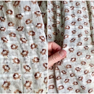 May include: Close-up of a white fabric with a brown floral pattern. The fabric has a subtle striped texture.