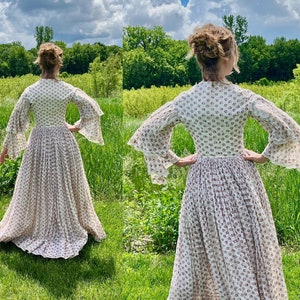 May include: A white dress with a floral pattern and long sleeves with ruffles. The dress has a fitted bodice and a full skirt.